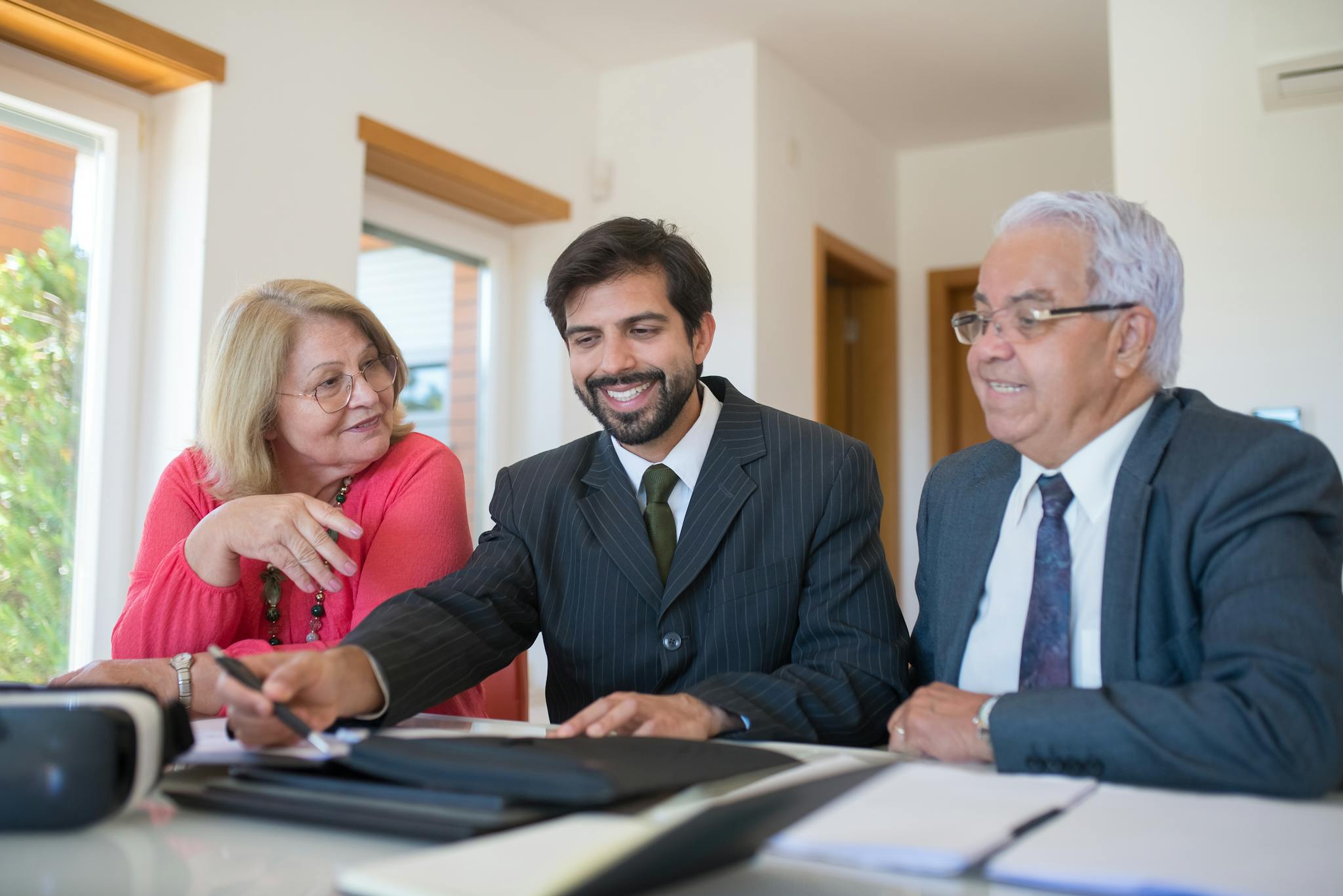 Professional realtor discussing real estate deal with senior couple in bright office setting.